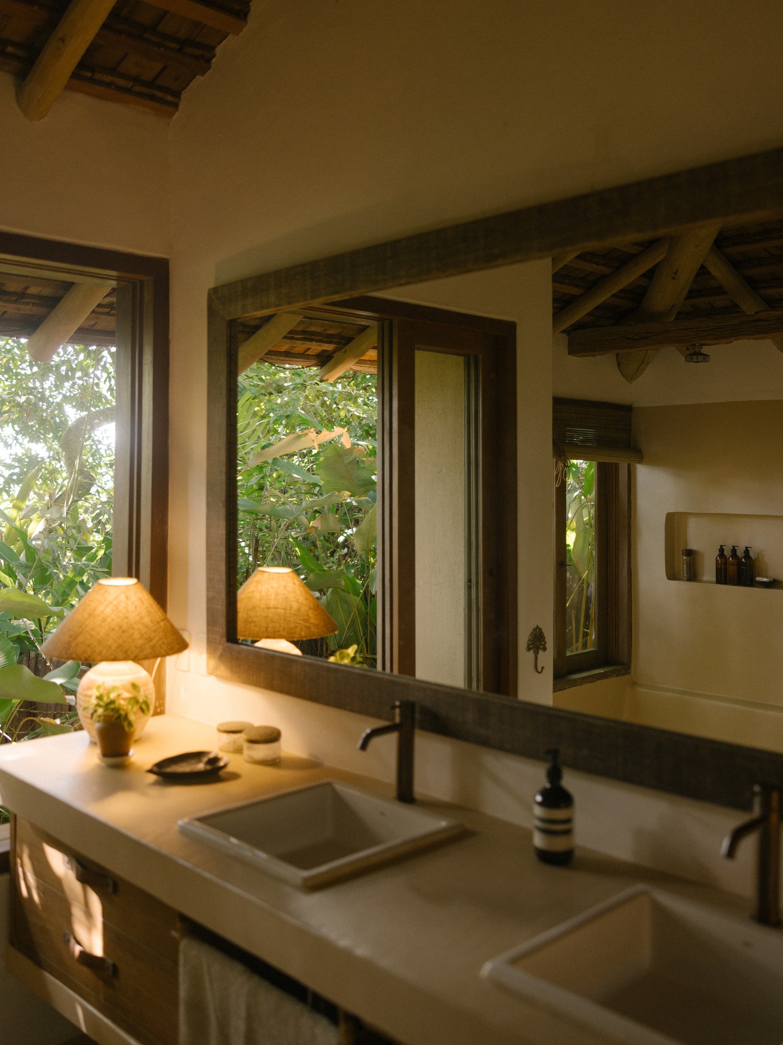 Badkamer met twee wastafels en uitzicht op de jungle