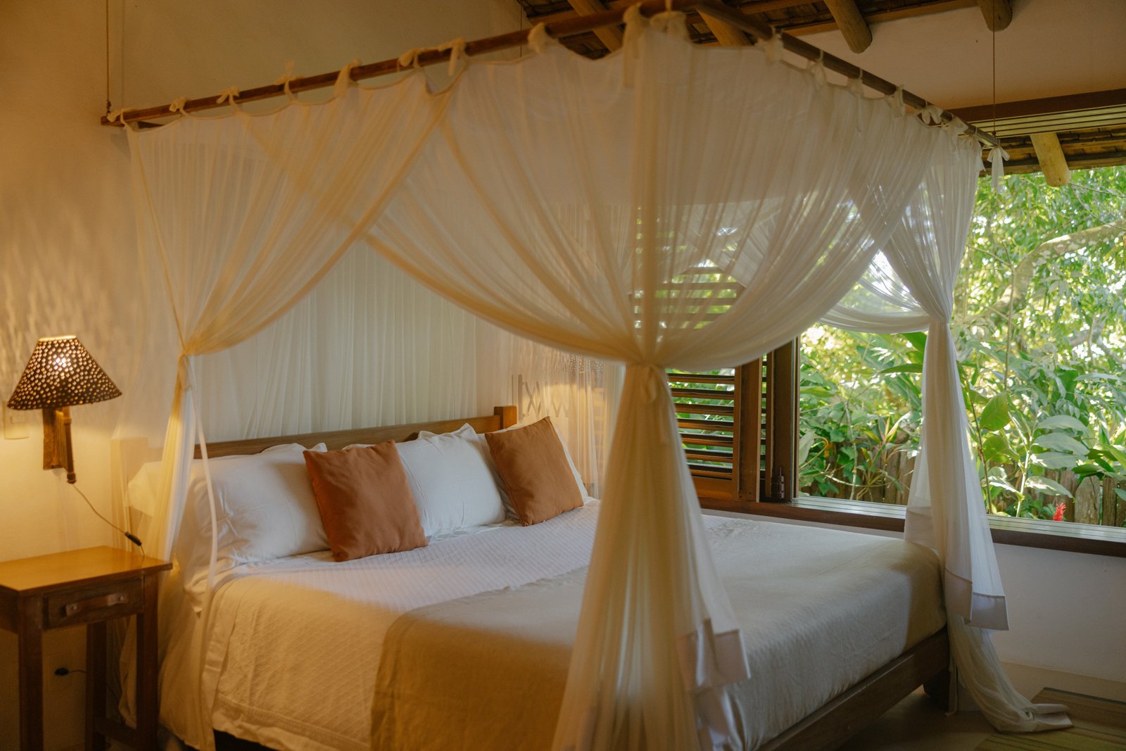 Private Room met groot bed onder een klamboe en uitzicht op het groen
